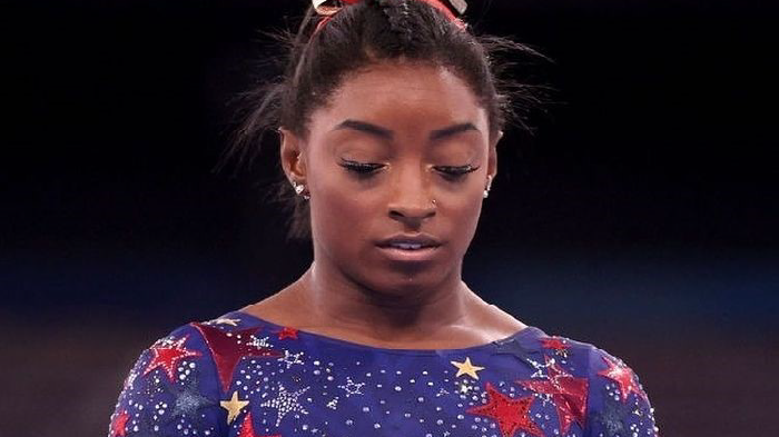 Simone Biles looking down at balance beam