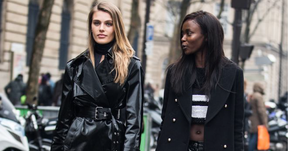 Two fashion models walking on the street with coats.