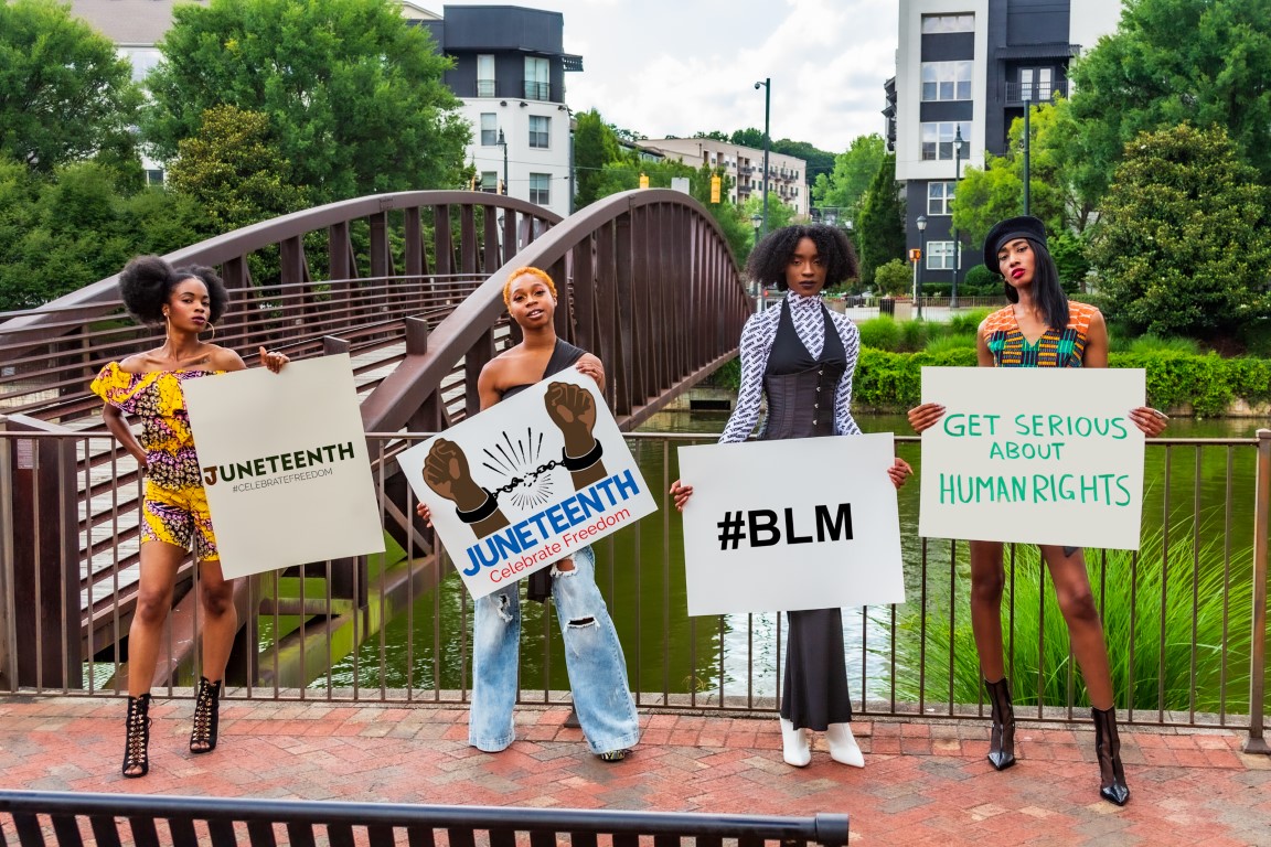 Juneteenth Advocates holding signs with Juneteenth, BLM, and Human Rights signs in front of bridge