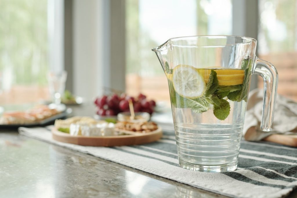 Close-up of a glassy pitcher of lemonade on stripped napkin prepared for a dinner party at home