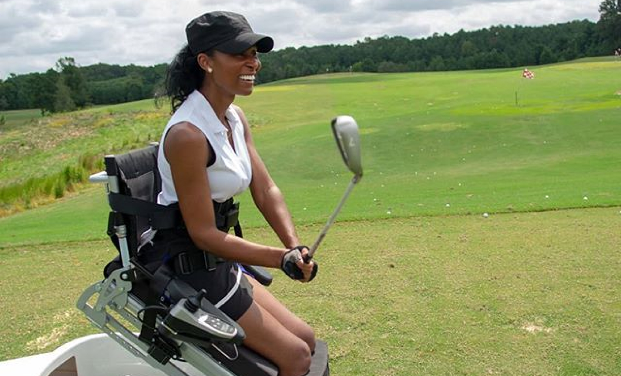 Tae McKenzie on golf course with assistive equipment on wheels holding golf club.