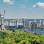 motherland monument among green trees on embankment in kiev