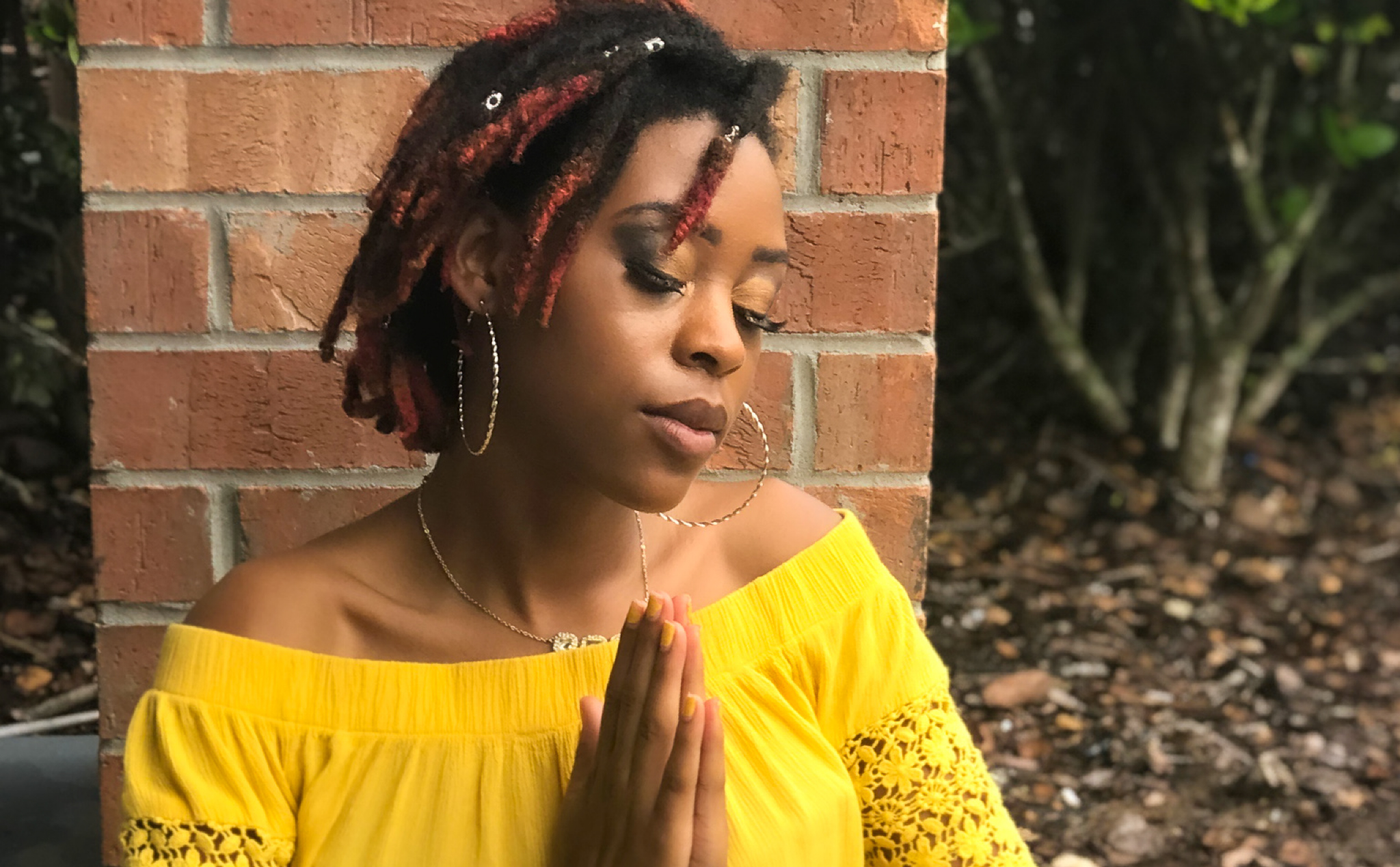 Young woman on the ground meditating with her hands clasped together.