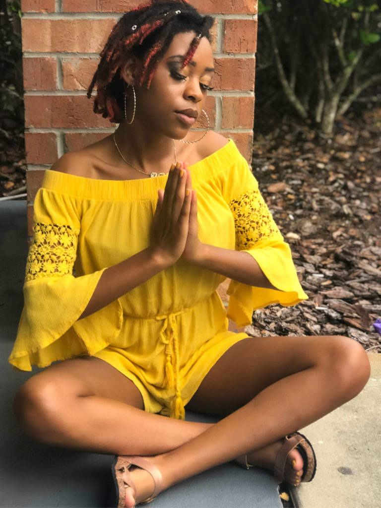 Young woman on the ground meditating with her hands clasped together.