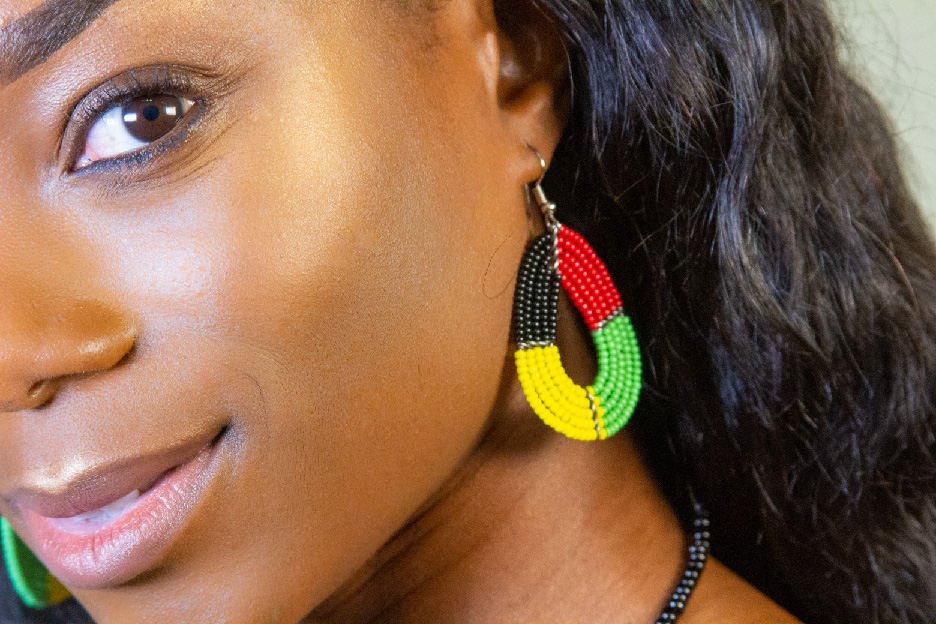 Model wearing a four-color bead earring with one eye visible